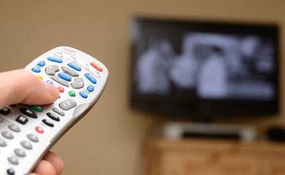 Image of hand holding TV remote pointing at television